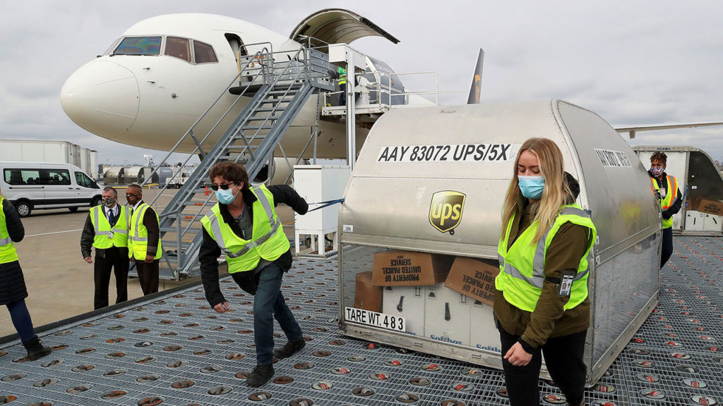 Los empleados de UPS mueven uno de los dos contenedores de envío de la vacuna Pfizer COVID-19 en la rampa del Aeropuerto Internacional Louisville Muhammad Ali en Louisville, Kentucky, EE. UU
