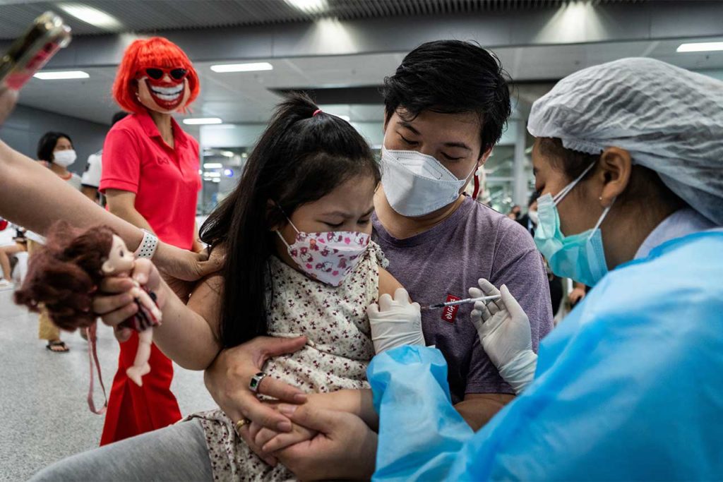 Niña vacunación vacuna A mascot is seen behind a child as she receives the Pfizer-