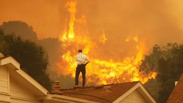 Un hombre en una azotea observa las llamas que se acercan al incendio de Springs el 3 de mayo de 2013, cerca de Camarillo, California. Getty Images