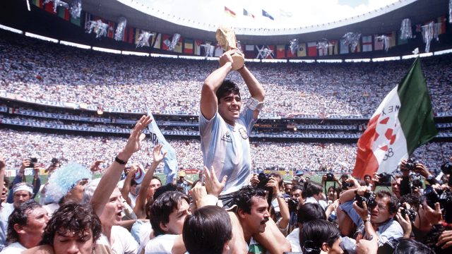 Argentina's captain Diego Maradona proudly holds aloft the FIFA World Cup trophy amongst masses of fans and photographers on the pitch after Argentina defeated West Germany 3-2 in the 1986 FIFA World Cup final to become world champions, at Estadio Azteca in Mexico City, Mexico on the 29th June 1986. (Photo by Bob Thomas Sports Photography via Getty Images)